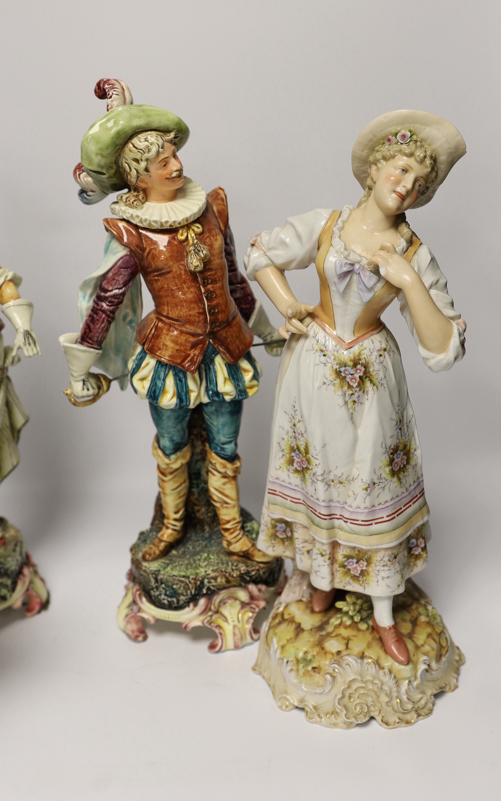 A pair of Volkstedt porcelain figures and a pair continental earthenware figures, 42cm